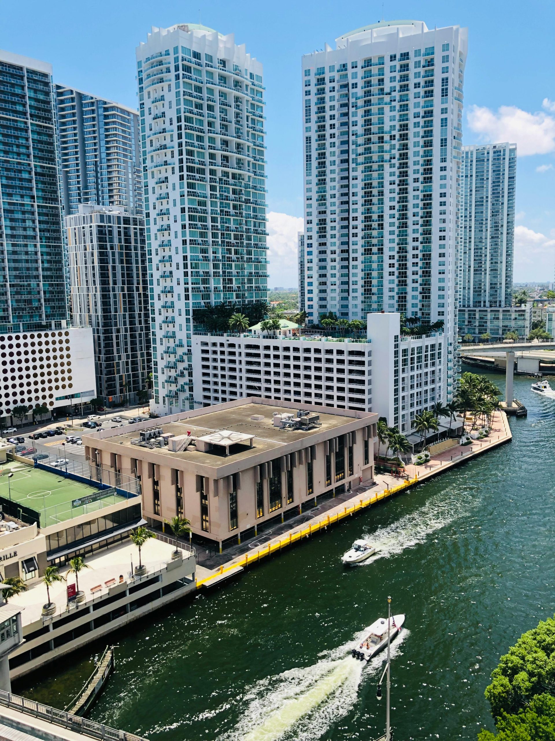 Aerial view of modern skyscrapers by a lively waterfront in a vibrant city.